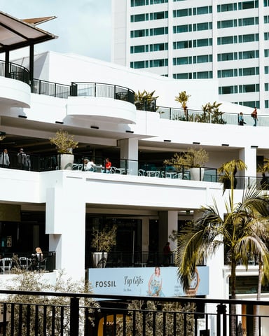 Modern outdoor shopping center with palm trees and balconies