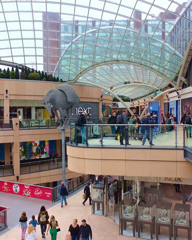 Multi-level indoor shopping mall with glass ceiling and retail stores